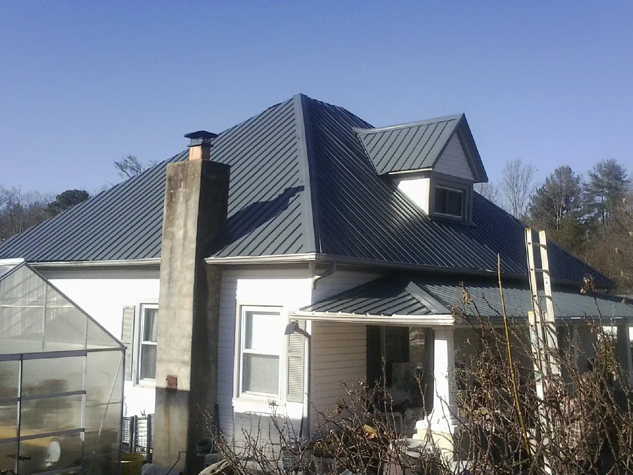 Dark blue standing seam metal roof on a white farmhouse with dormer — Slate & Tile Roof Repair by Roofing Brothers in Entiat