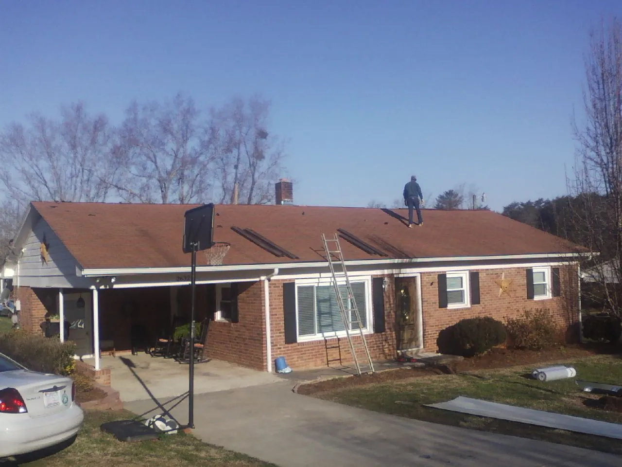 Roofer stripping a shingle roof on a brick ranch before metal panels in Entiat