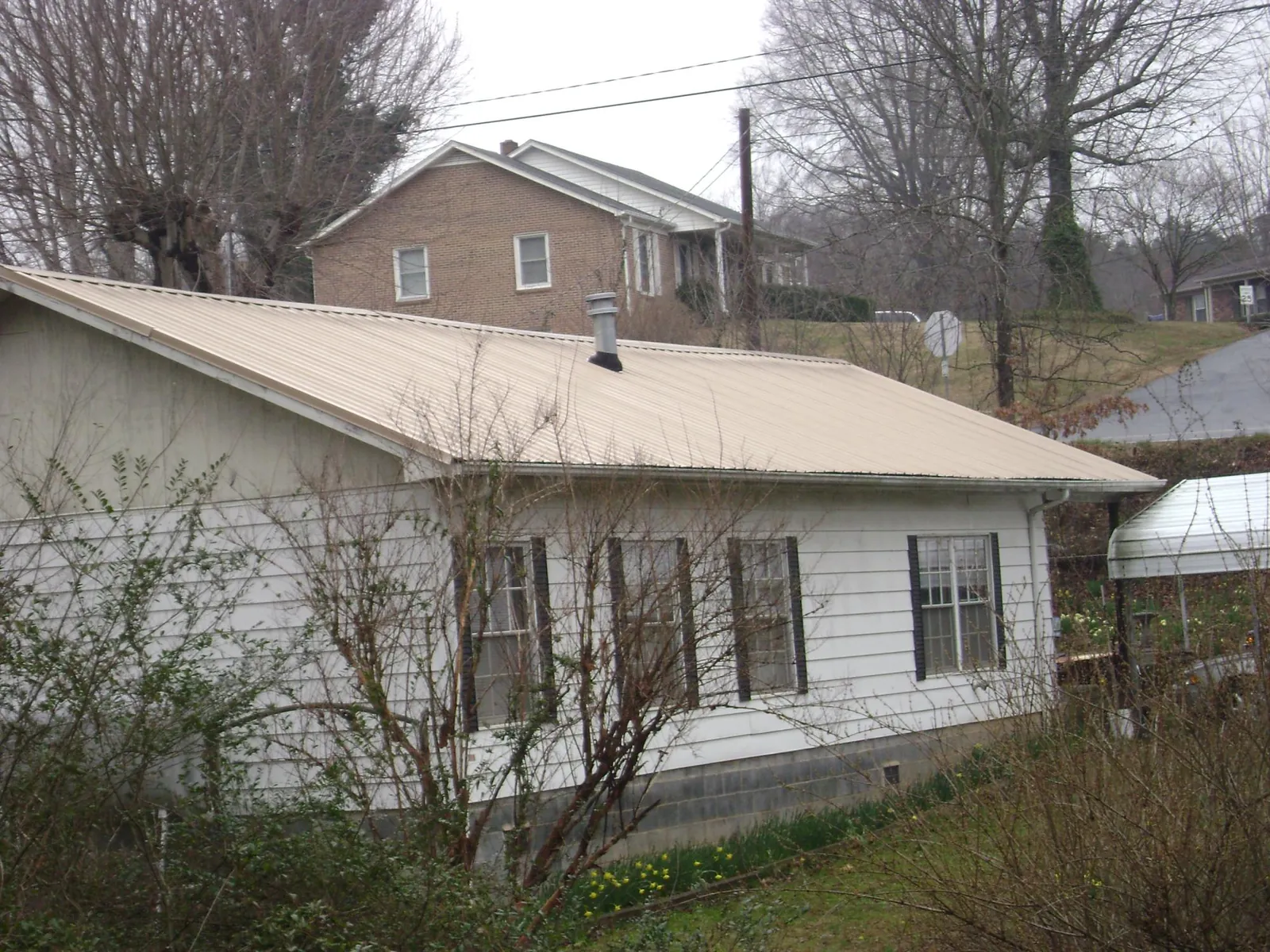Tan metal roof on a white sided house set into a hillside — Commercial Roofing by Roofing Brothers in Entiat