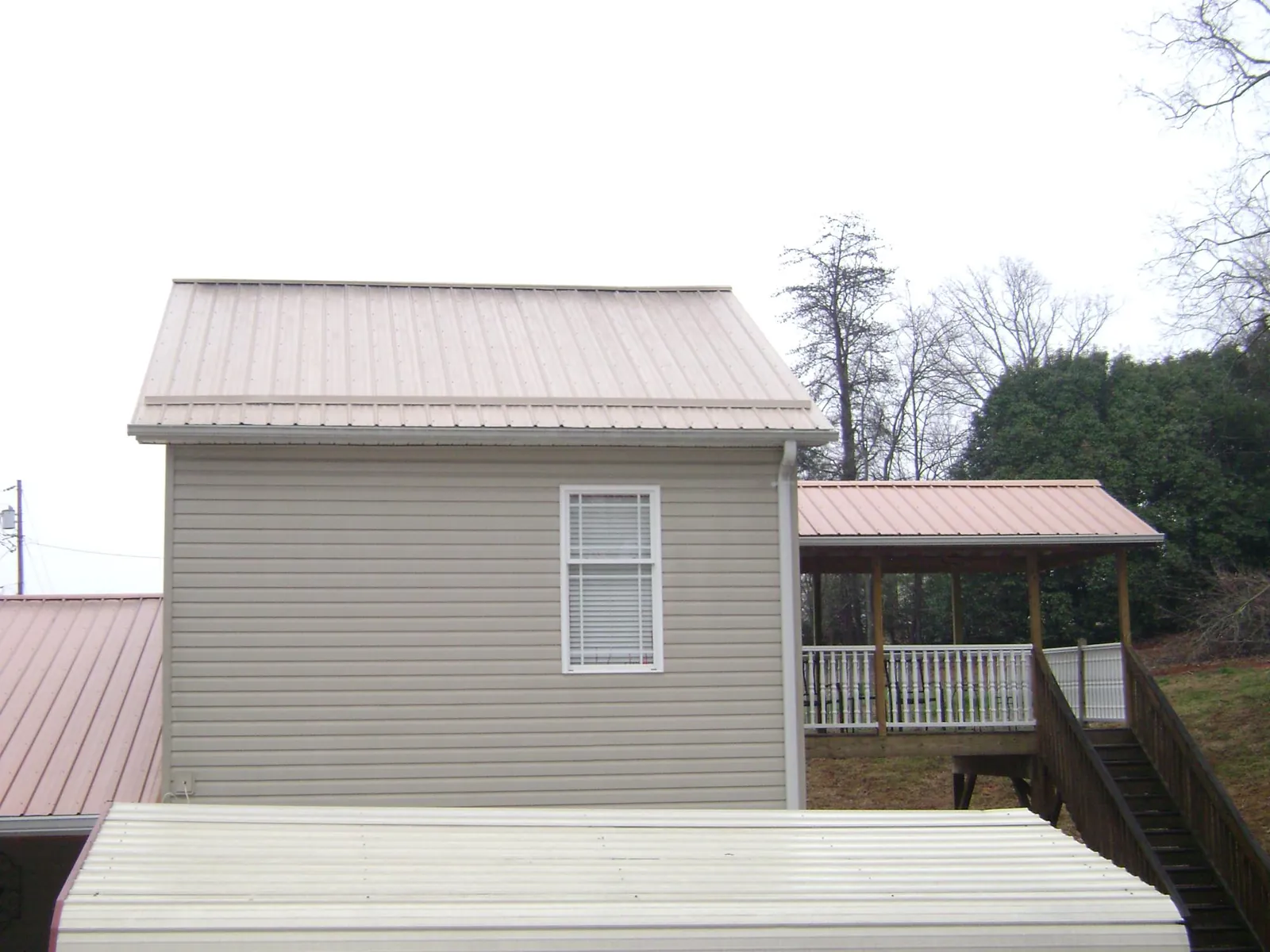 Tan metal roofs on a two story addition and attached porch, from a Roof Replacement job in Entiat
