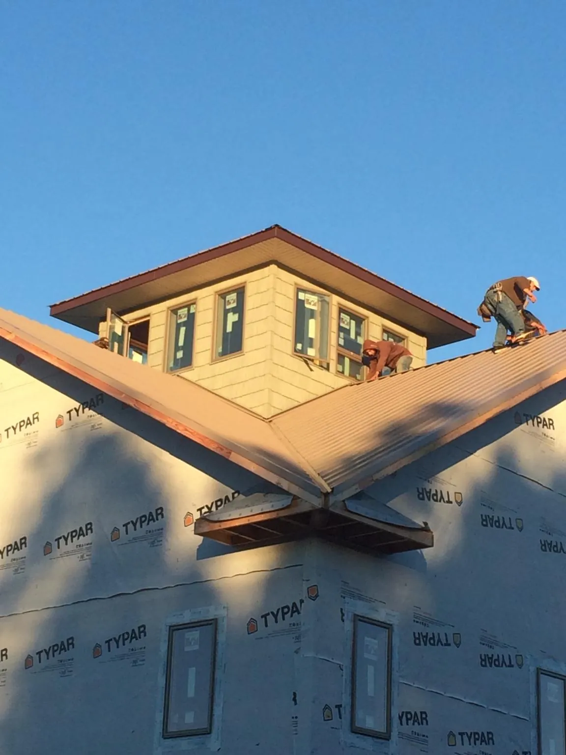 Roofers working around a rooftop cupola on a new metal roof at sunset — Roof Waterproofing in Entiat by Roofing Brothers